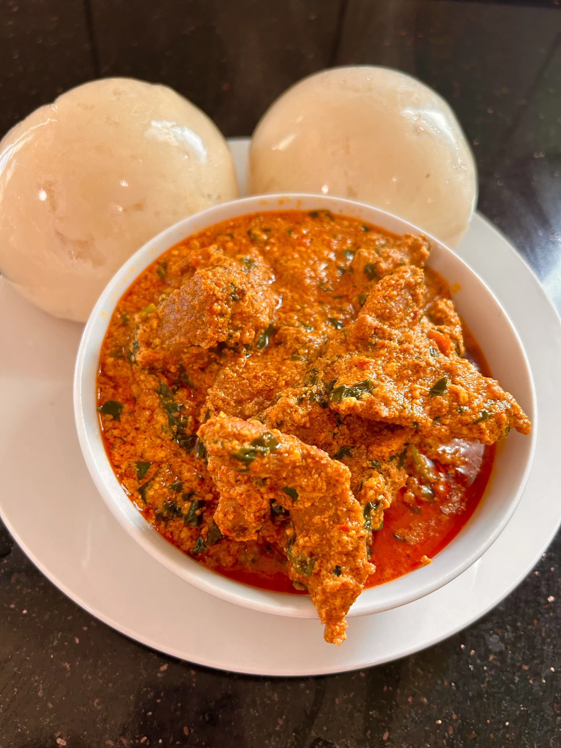 A rich bowl of Nigerian Egusi soup served with assorted swallow